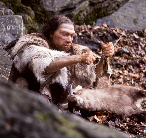 Neanderthal man squatting down with hunted animal.